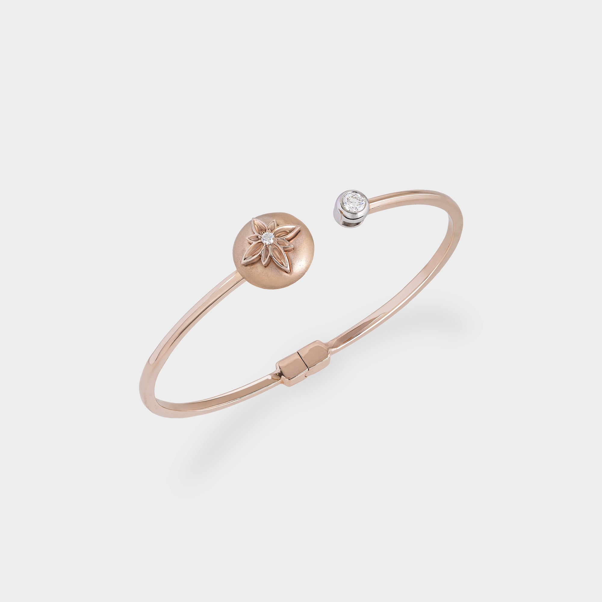 Rose gold bracelet with a round charm and diamond on a light gray background
