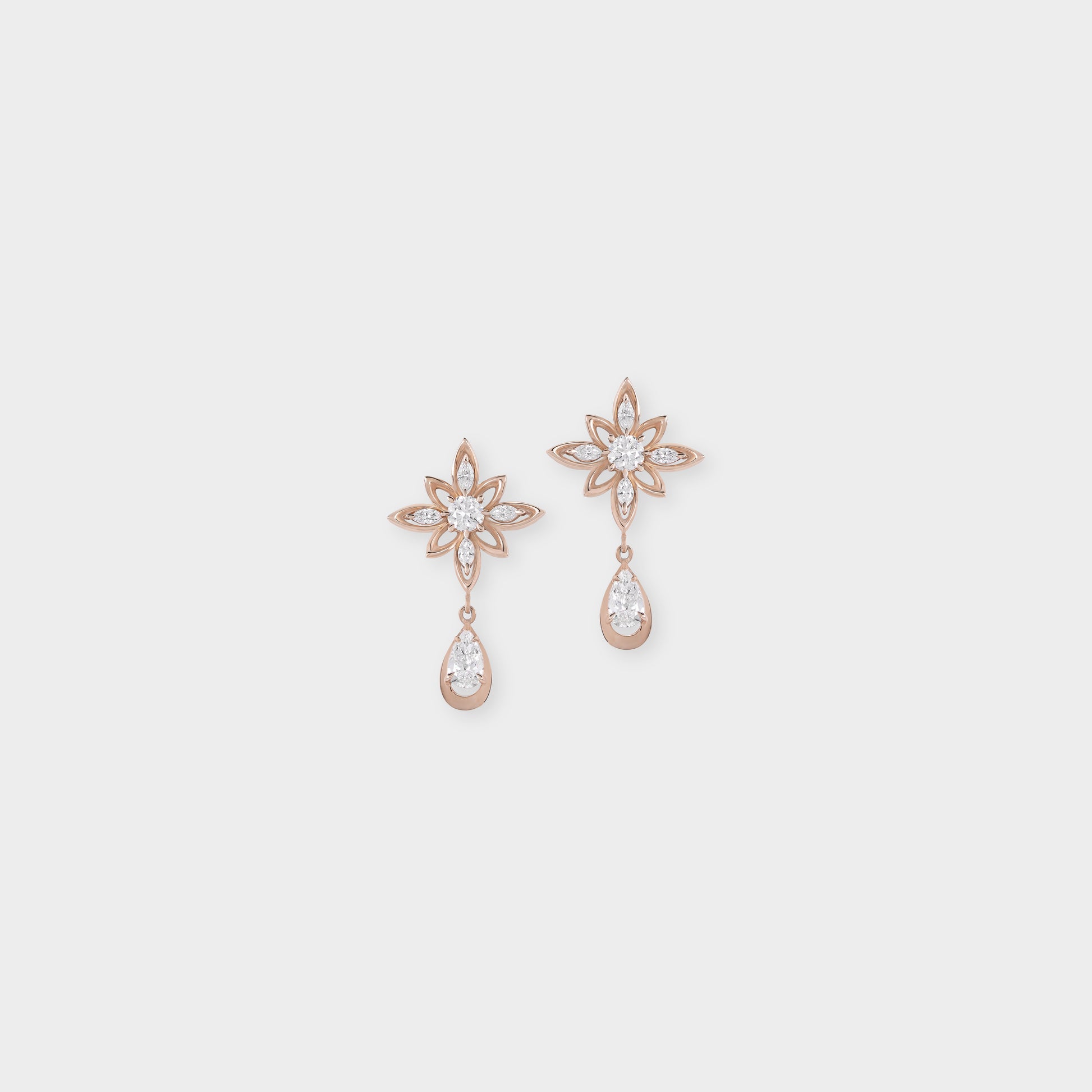 Pair of rose gold earrings with star and teardrop designs on a light gray background