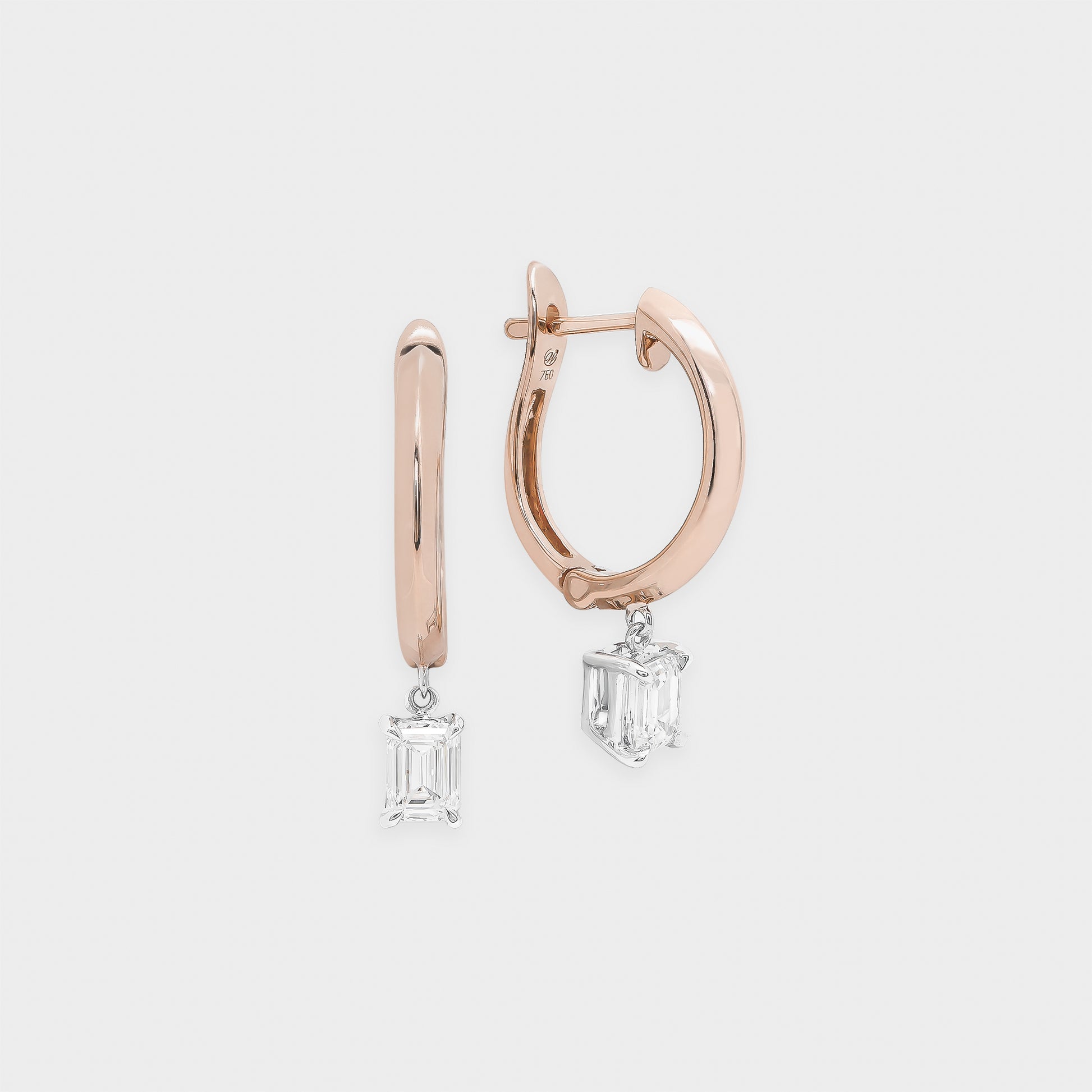 Rose gold hoop earrings with emerald-cut gemstones on a light gray background