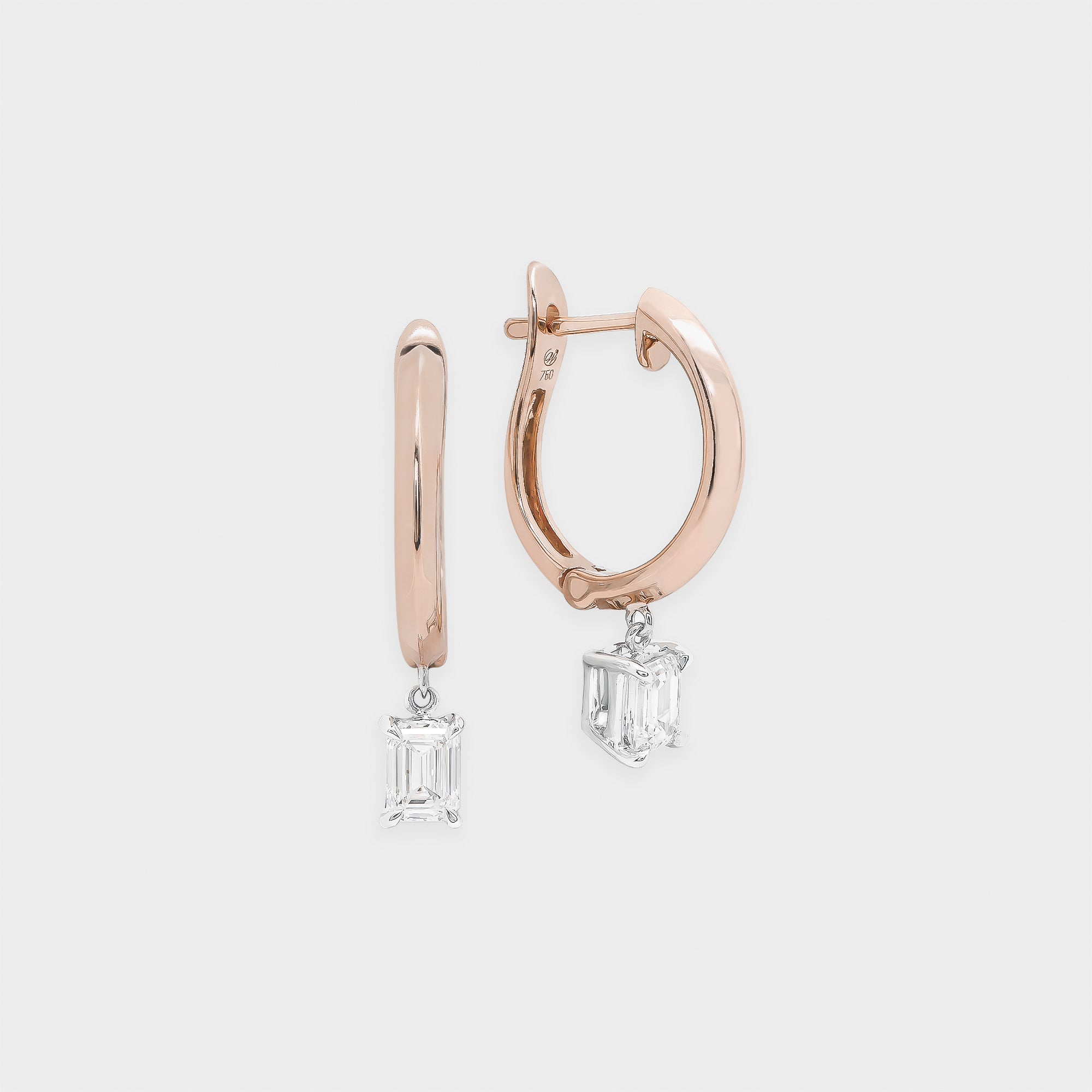 Rose gold hoop earrings with emerald-cut gemstones on a light gray background