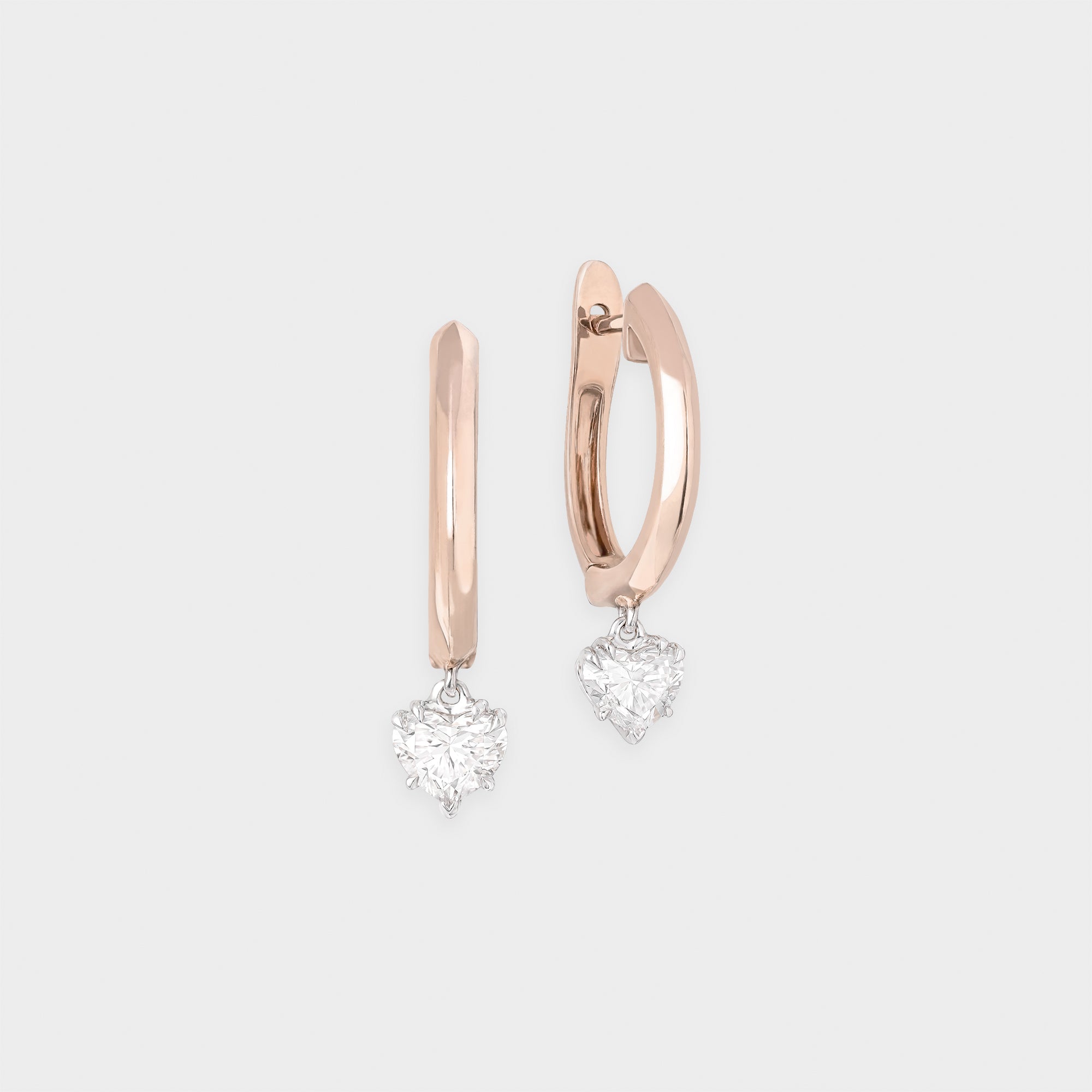 Rose gold hoop earrings with heart-shaped diamond pendants on a light gray background