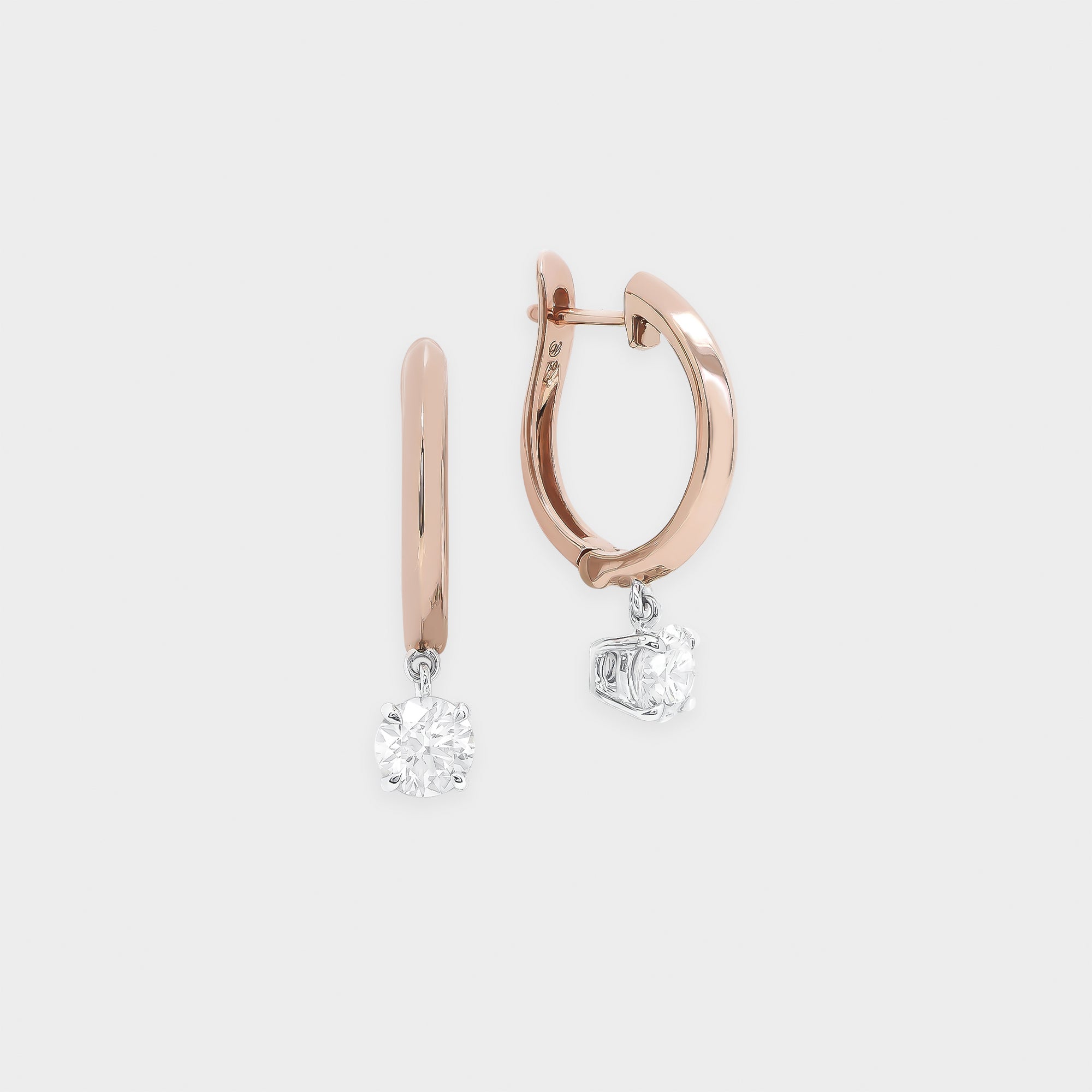 Rose gold hoop earrings with diamond drops on a light gray background