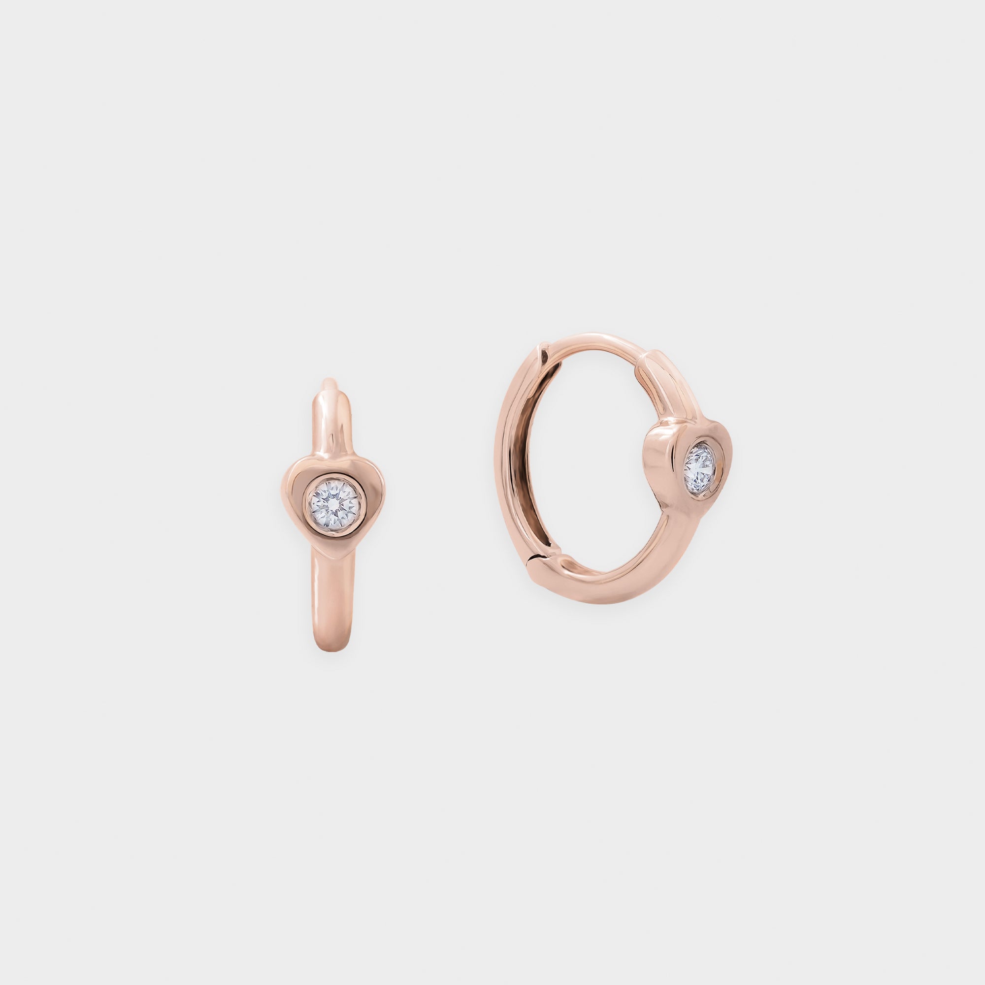 Rose gold hoop earring with embedded diamond on a light gray background