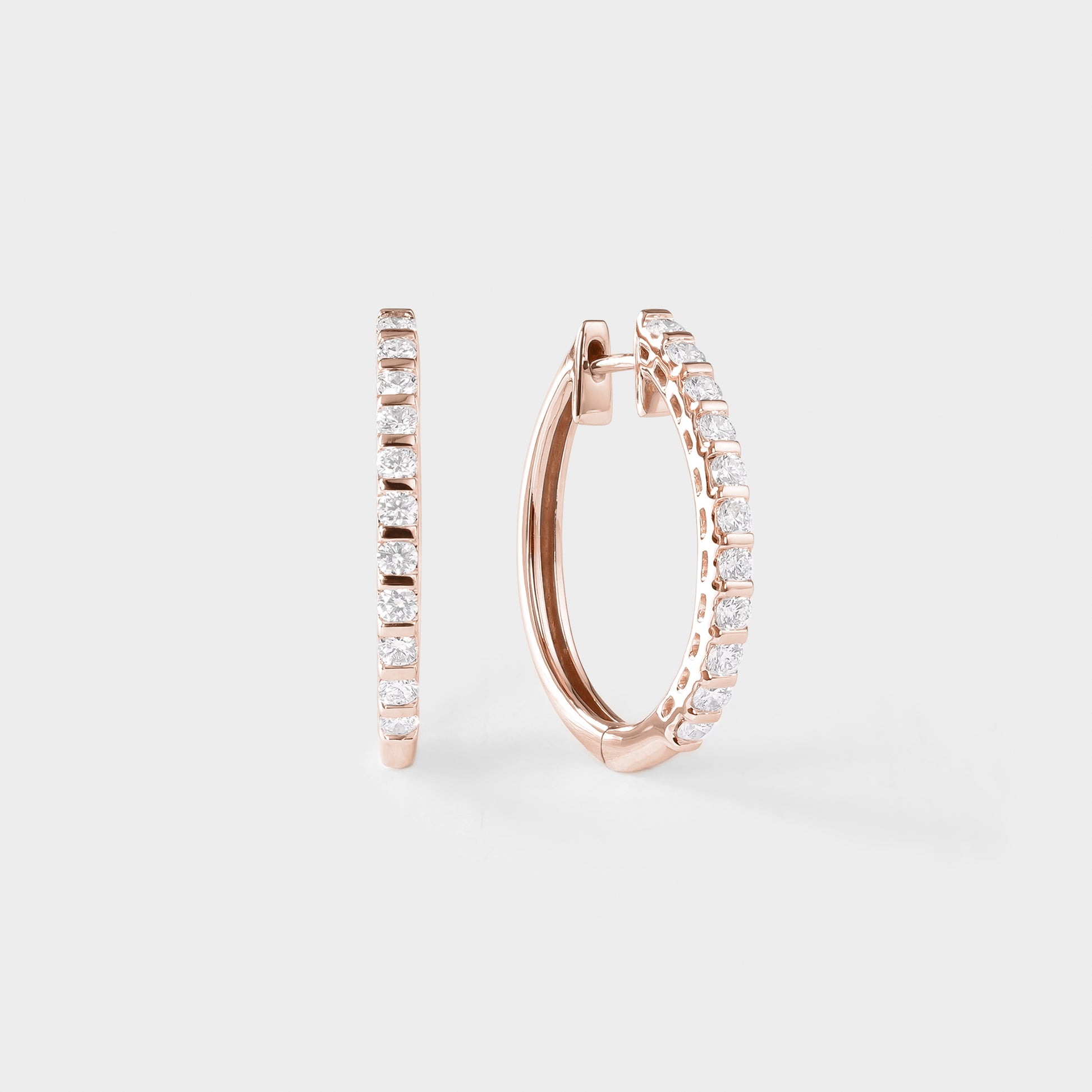 Rose gold hoop earrings with clear gemstones on a light gray background