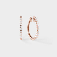 Rose gold hoop earrings with clear gemstones on a light gray background