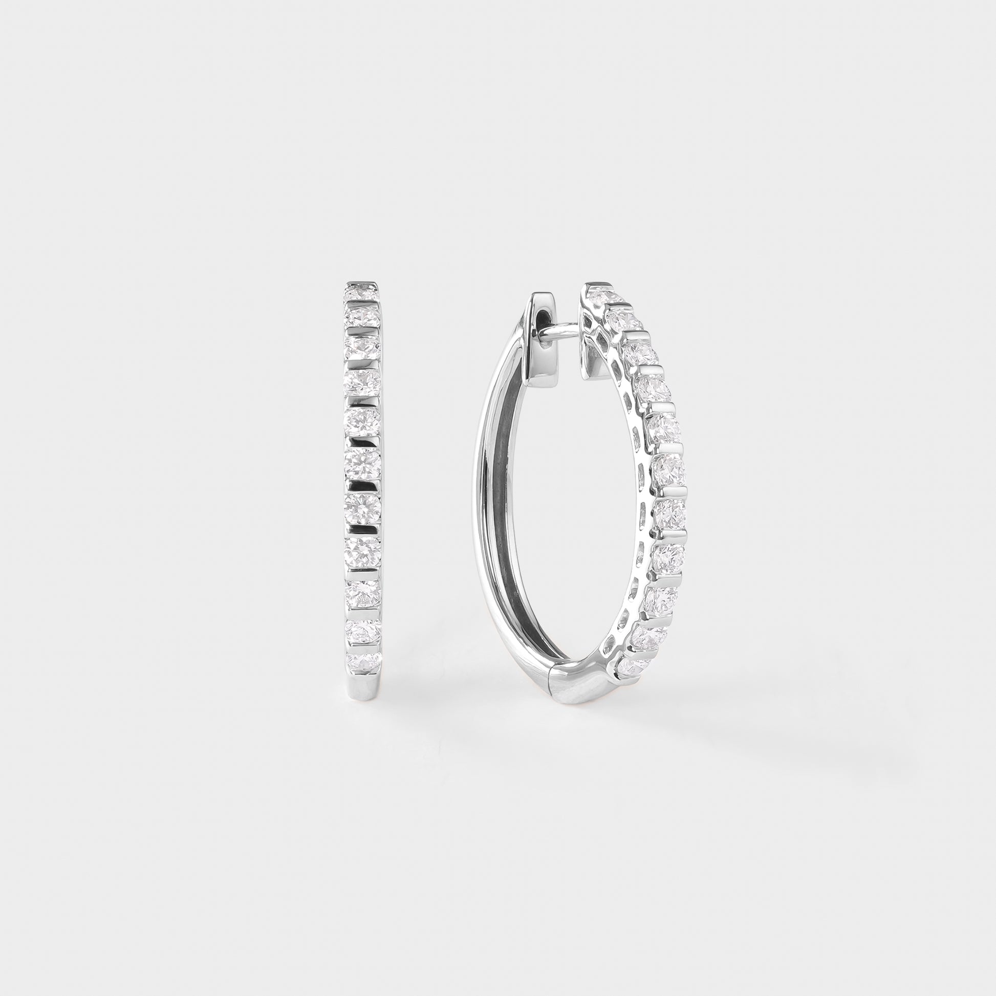 Pair of white gold hoop earrings with clear diamond on a light gray background