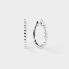 Pair of white gold hoop earrings with clear diamond on a light gray background