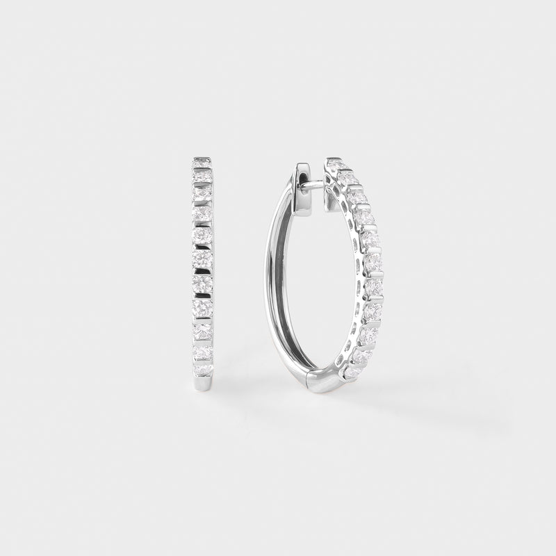 Pair of white gold hoop earrings with clear diamond on a light gray background