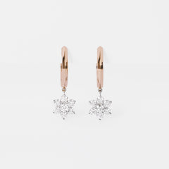 Rose gold hoop earrings with diamond Sunflower pendants on a light gray background